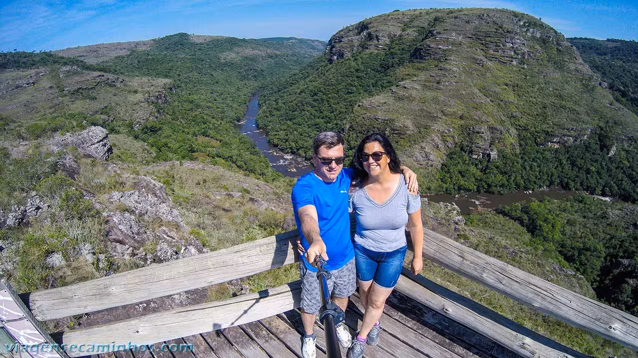 Couple enjoying panoramic view of Cânion do Guartelá from a wooden deck overlooking the valley.