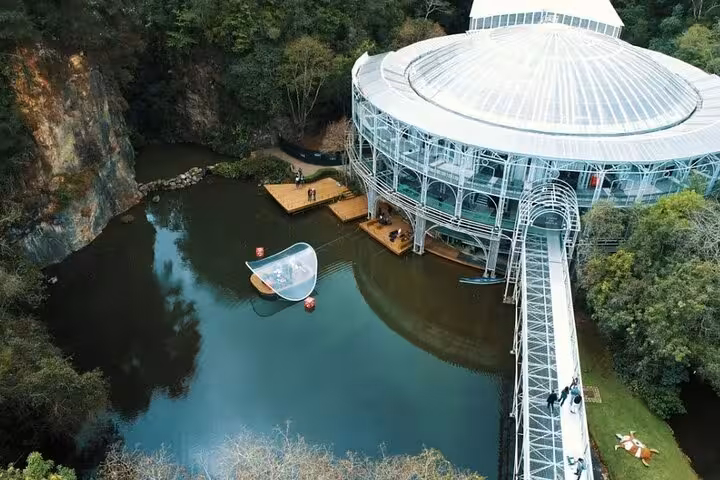 Aerial view of wire opera house surrounded by lush greenery and lake on Curitiba city tour.