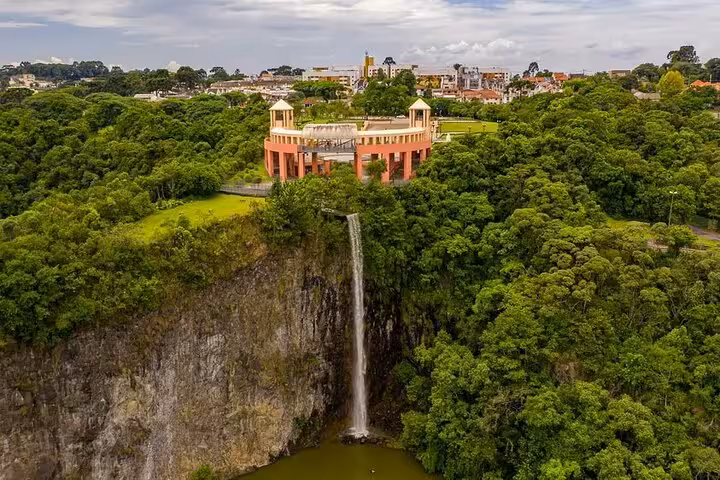 Aerial view of Curitiba's Tangua Park featuring lush greenery and a stunning waterfall with a scenic overlook.