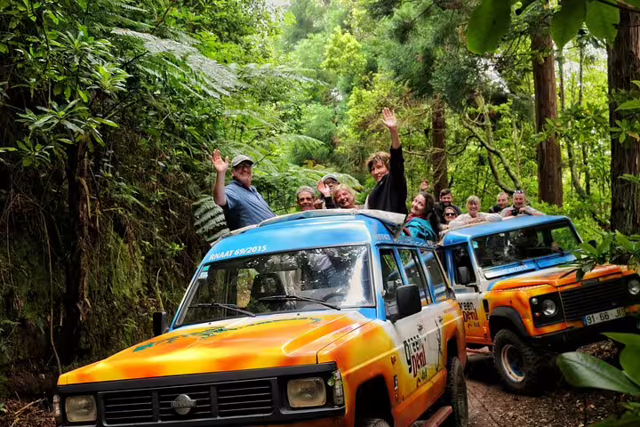 Adventurous tourists enjoy a vibrant 4WD tour through lush forests on the Curral das Freiras & Peaks route in Madeira.
