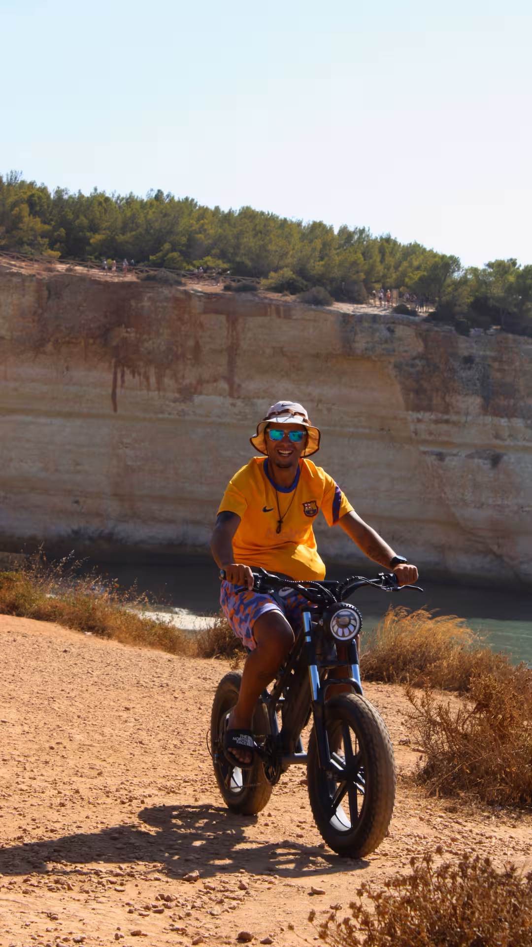 Smiling cyclist on an e-bike riding dusty Algarve clifftop trail on the Seven Hanging Valleys scenic bike tour