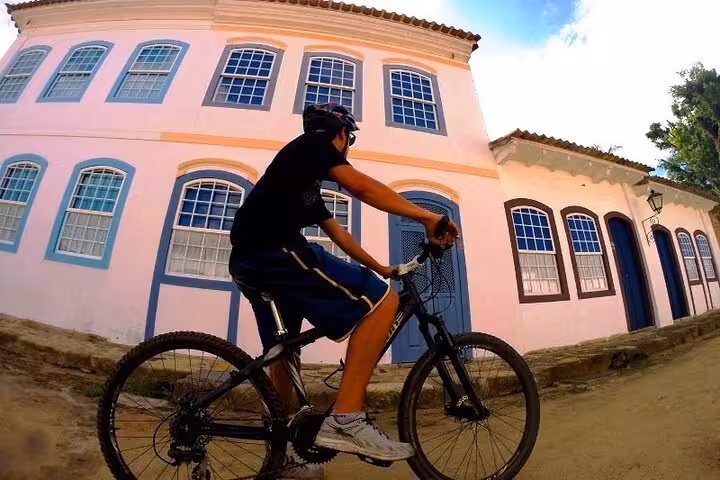 Cyclist riding past colorful colonial architecture in Paraty, capturing the blend of culture and adventure with Paraty Tours.