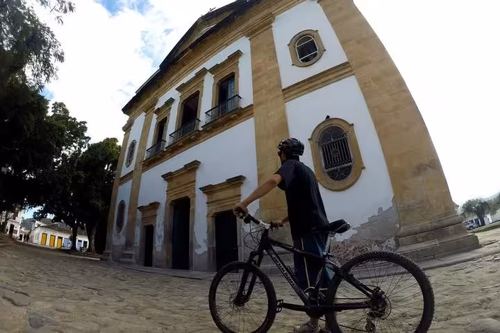 Cyclist exploring historic architecture in Paraty on a guided bike tour with Paraty Tours.