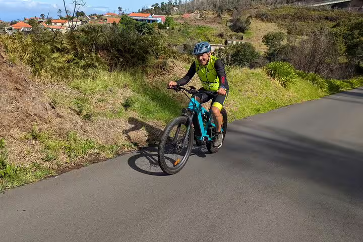 Cyclist enjoying a scenic bike tour on the west coast of Madeira, surrounded by lush greenery and picturesque views.