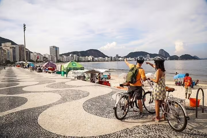 Two cyclists pause to admire Copacabana Beach view, Rio, highlighting the vibrant scenery of the bike tour.