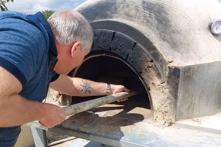 Guest baking bread in a traditional Cypriot stone oven during an authentic cultural workshop and wine tour