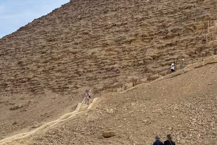 Hikers on trail beside Dahshur Red Pyramid slope during private tour from Cairo to Saqqara and Memphis