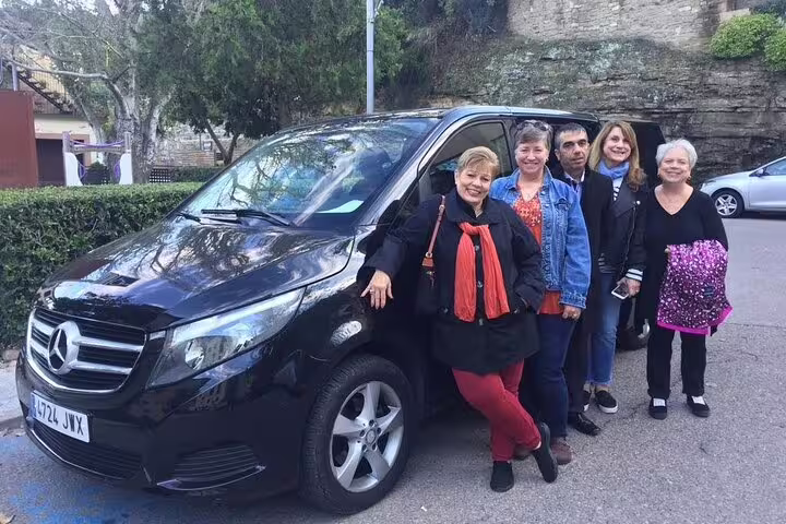 Group of travelers posing with a black Mercedes van, ready for the Dalí Museum and Girona day trip.