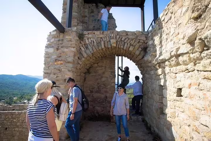 Tourists exploring ancient stone architecture on a sunny day during the Dalí Museum and Girona tour.