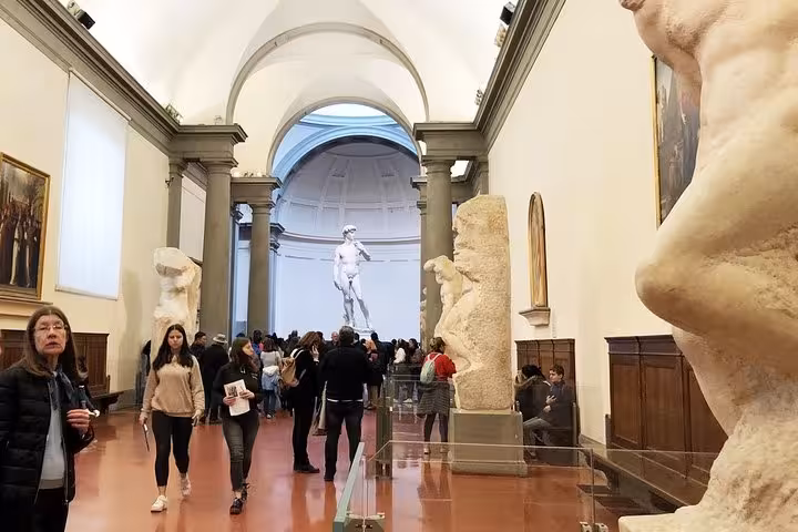 Tourists exploring the gallery leading to Michelangelo's David on a guided tour at the Accademia in Florence.