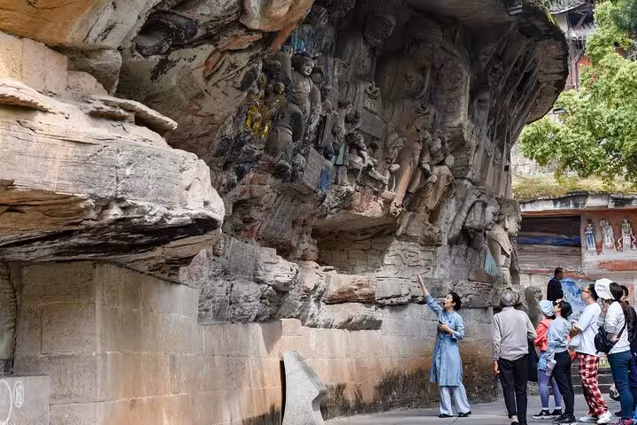 Tourists admire intricate Dazu Rock Carvings in Chongqing during a private charter tour, showcasing ancient artistry.
