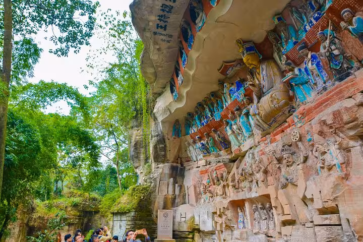 Tourists admire the intricate Dazu Rock Carvings nestled in lush greenery during a private charter tour from Chongqing.