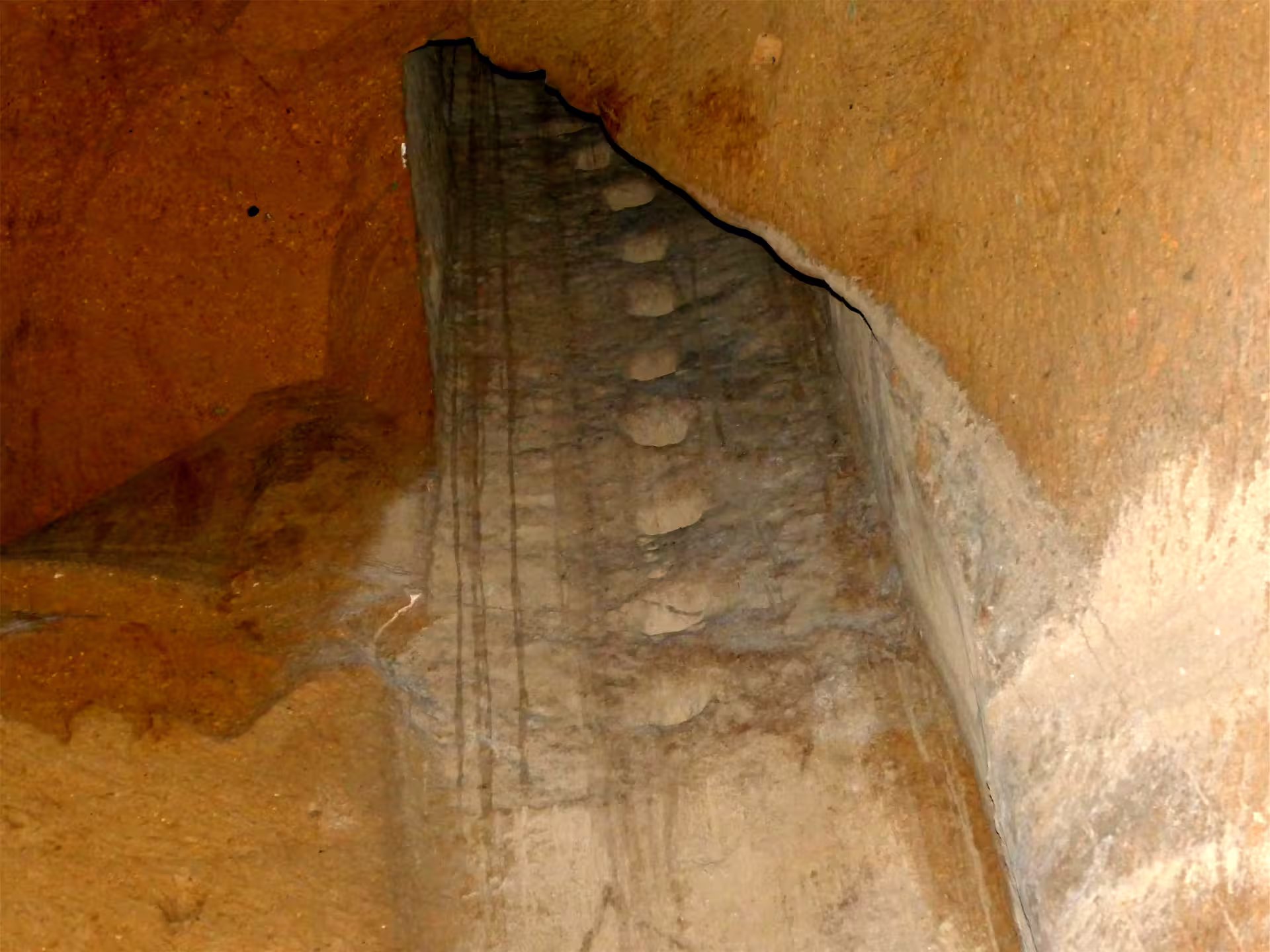 Close-up of carved rock channel and worn stone steps along the Decumano Sommerso route in the Lapis Museum underground Naples