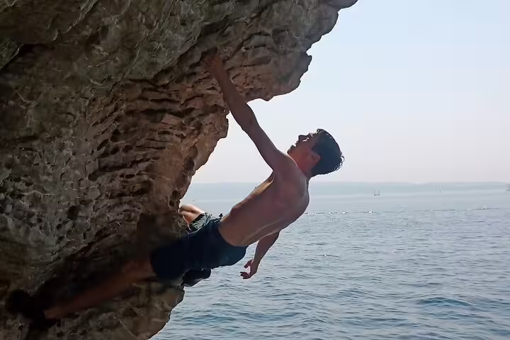 Deep water soloing in Split, Croatia, climber traversing limestone overhang above the Adriatic Sea