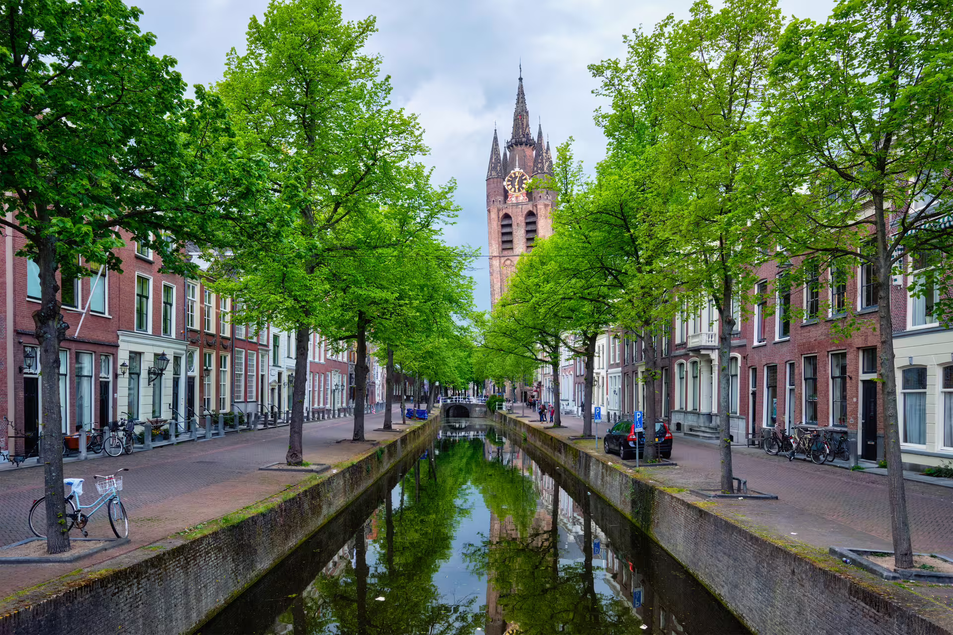 Delft canal with bicycles and Nieuwe Kerk tower, ideal stop on a 1-day walking tour audioguide