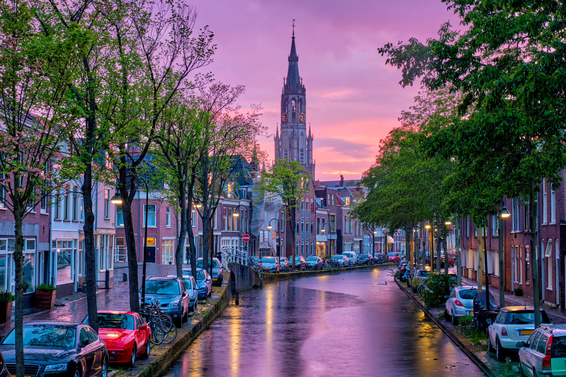 Delft canal at sunset with Nieuwe Kerk tower, scenic stop on Delft 1-day walking tour audioguide