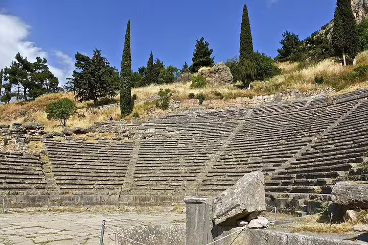 Ancient stone amphitheater in Delphi under a clear blue sky, perfect for a historical private day trip from Athens.