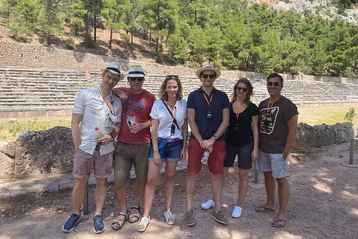 A group of tourists enjoying a sunny day at the ancient ruins of Delphi during a private full-day tour.