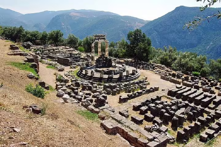 Delphi archaeological site ruins and circular sanctuary with mountain views on a guided small group day tour from Athens