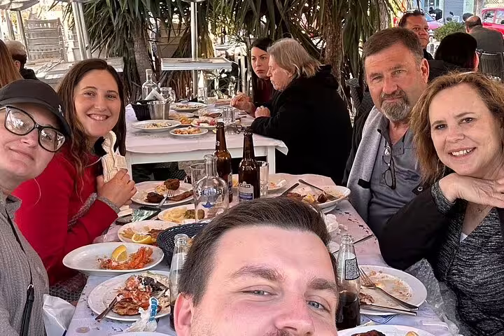 Travelers enjoying Greek taverna dinner during Delphi and Meteora private day trip from Athens