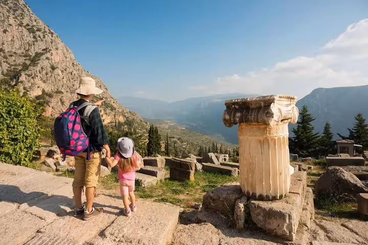 A family enjoys breathtaking views of Delphi's ancient ruins and mountains, perfect for a private full-day tour adventure.