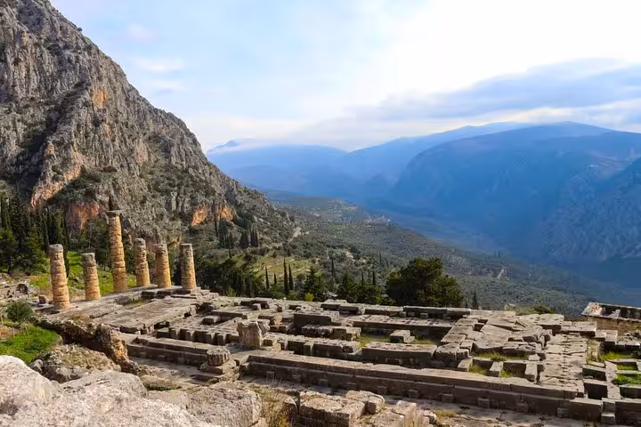Explore ancient ruins of the Temple of Apollo in Delphi with breathtaking mountain views on this private full-day tour.