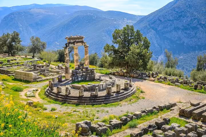 Explore the ancient ruins of the Tholos of Delphi surrounded by stunning mountainous landscapes on a private full-day tour.