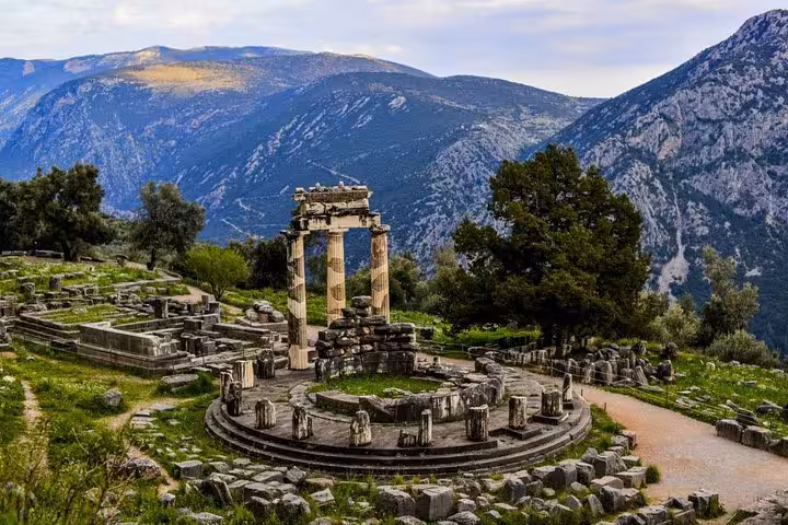 Ancient Tholos of Delphi ruins with mountain views, highlight of Mystical Delphi luxury day tour from Athens