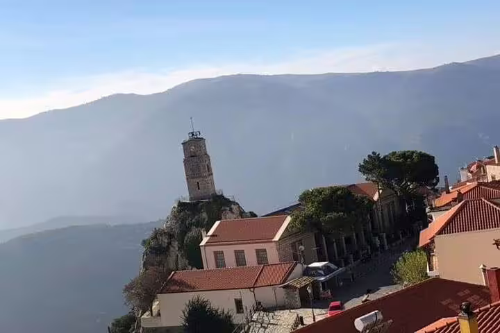 Delphi village rooftops and clock tower at sunset, view on 2-day private tour to Meteora and Delphi