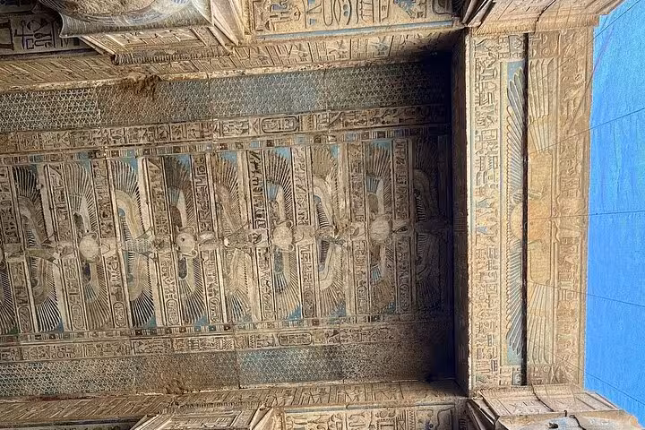 Ornate ceiling with detailed winged sun disk carvings in Dendera Temple, highlighting Egyptian architectural beauty.