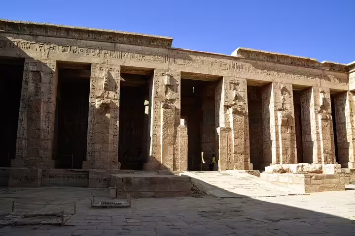 Dendera Temple colonnade with carved pillars under blue sky, highlight of Dendera and Abydos day tour
