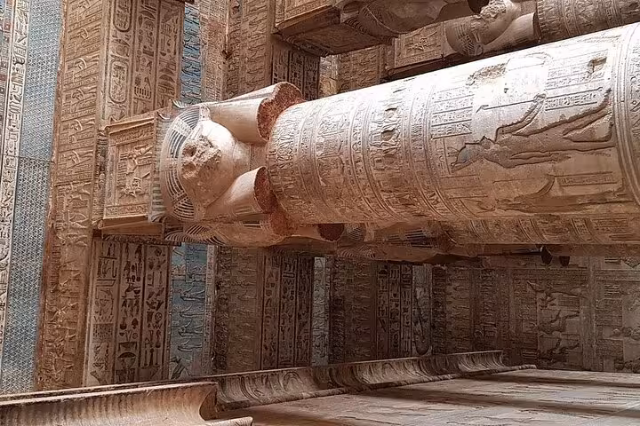Massive stone columns adorned with ancient carvings at Dendera Temple, showcasing Egyptian architectural grandeur.