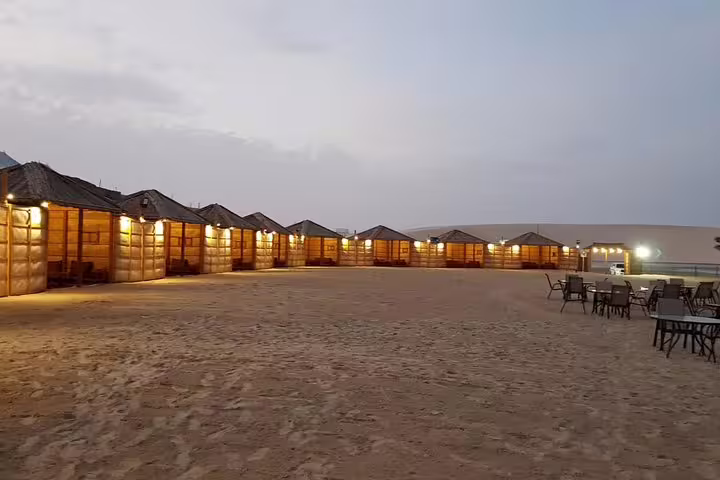 Desert camp with illuminated cabanas at dusk for a premium full-day safari experience.