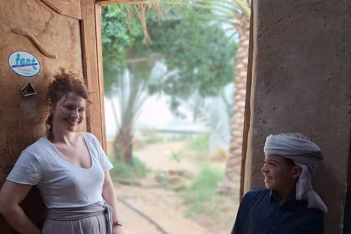 Smiling visitors at a traditional entrance, experiencing the cultural charm of Egypt on an all-inclusive desert camping trip.
