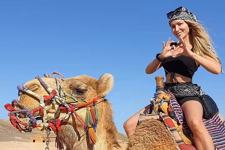 Tourist riding camel in Hurghada desert on Jeep safari with Bedouin village dinner and stargazing experience