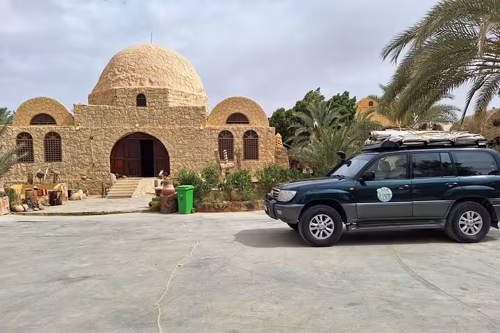 Traditional desert lodge with a 4x4 vehicle parked outside, perfect for all-inclusive private overnight camping tours.