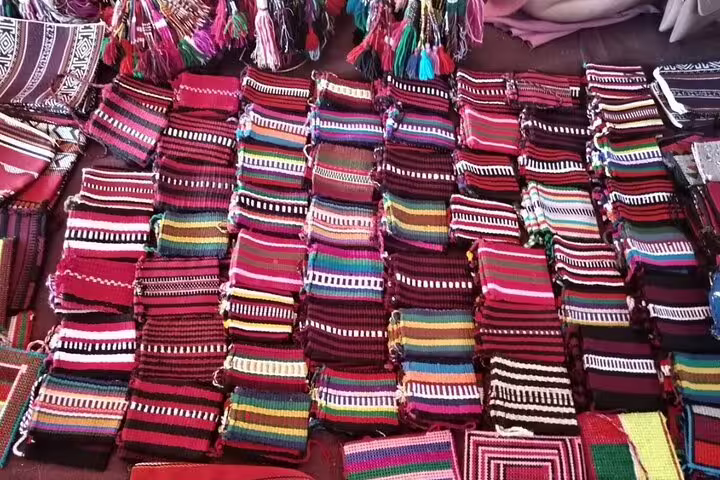 Colorful woven textiles displayed at a vibrant desert market during a private full day camel ride tour.