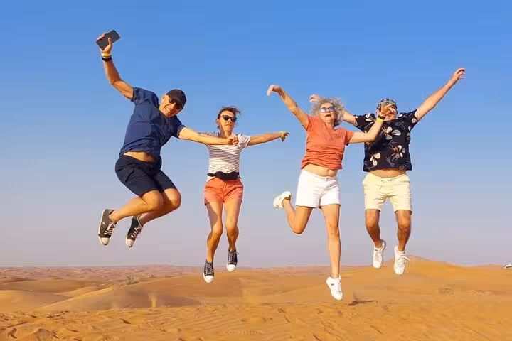 Friends jumping on Ras Al Khaimah desert safari dunes, adventure tour with camel ride and BBQ dinner