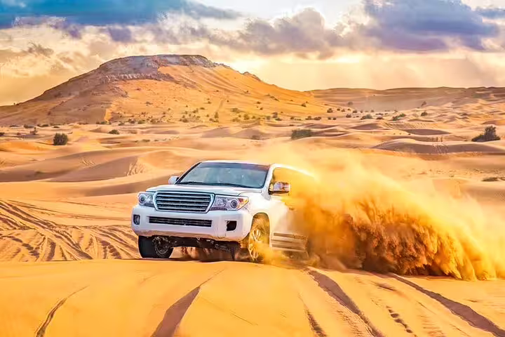 White SUV navigating golden sand dunes under a vibrant sky during a thrilling Desert Safari Dubai adventure.