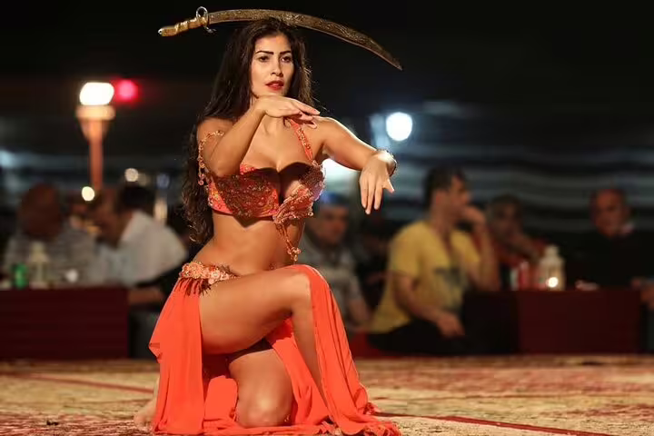 Performer in traditional attire balances a sword during a captivating live show at Dubai's desert safari with BBQ dinner.