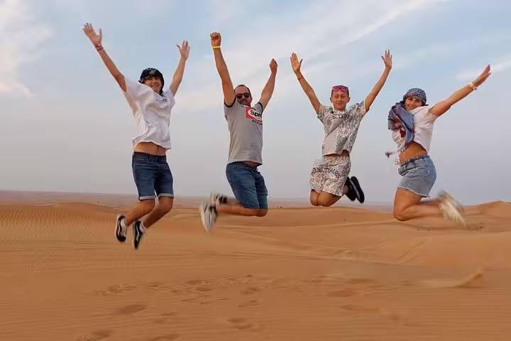 Friends jumping on Ras Al Khaimah desert safari dunes, a fun stop before camel ride and BBQ dinner