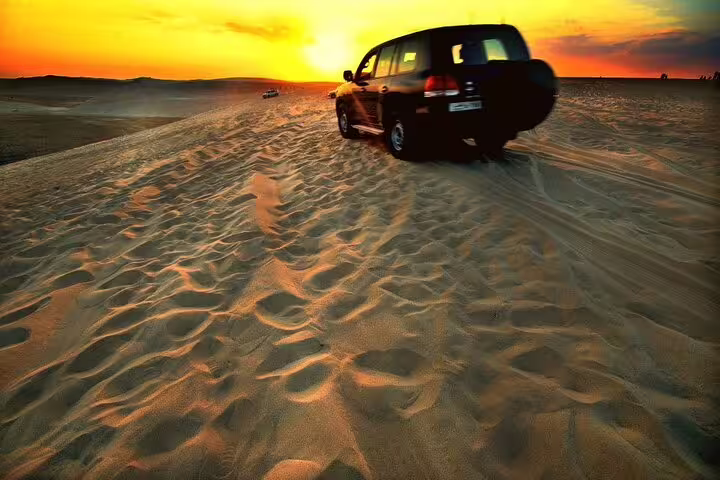4x4 vehicle navigates golden dunes during a breathtaking desert safari sunset, perfect for adventure seekers.