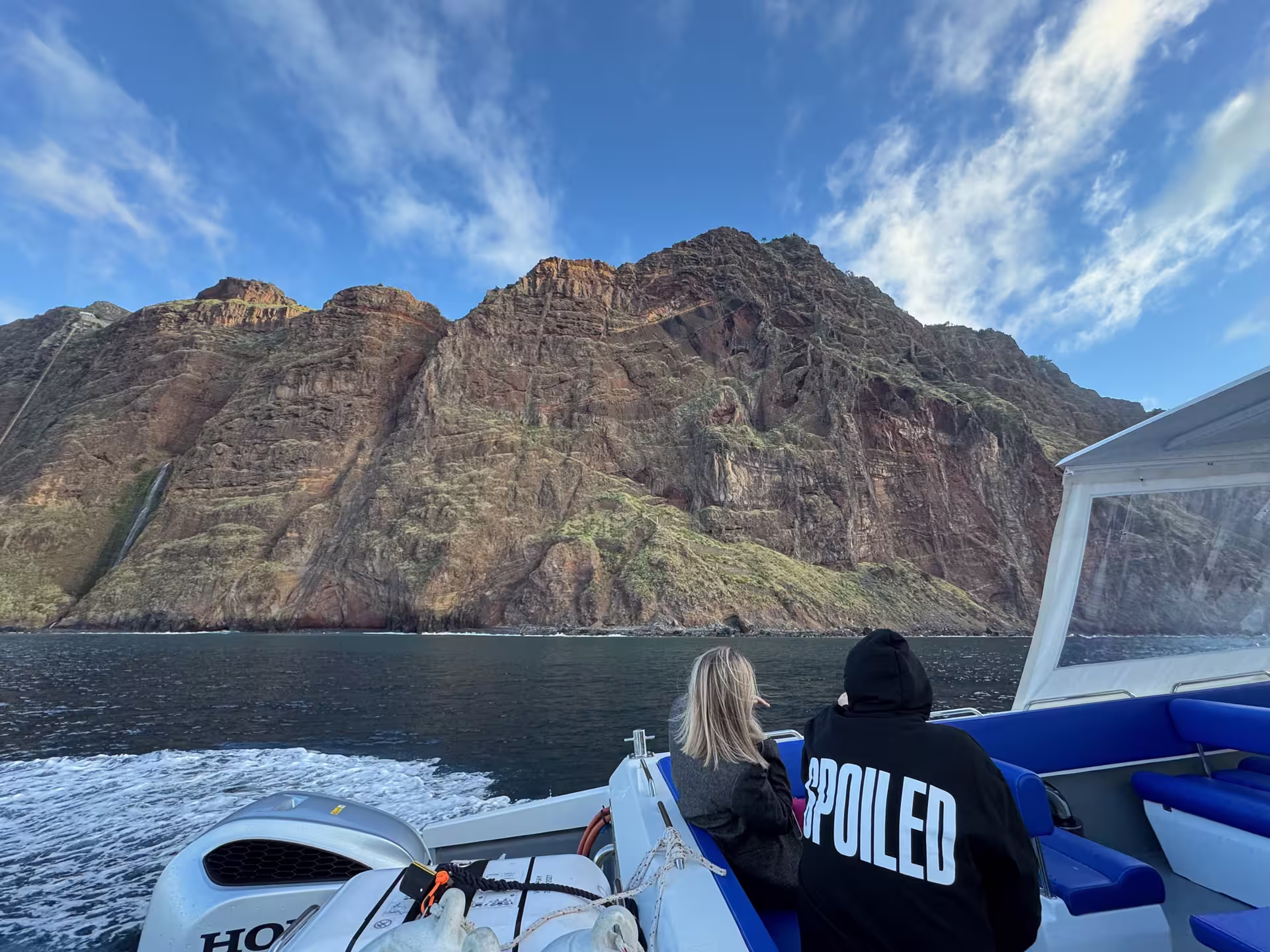 Tourists enjoying scenic views of rugged cliffs from a boat on Desertas Island Tour.