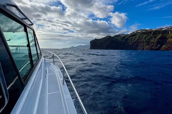 Yacht navigating the vibrant blue waters near Desertas Island cliffs, showcasing breathtaking views and nature exploration.
