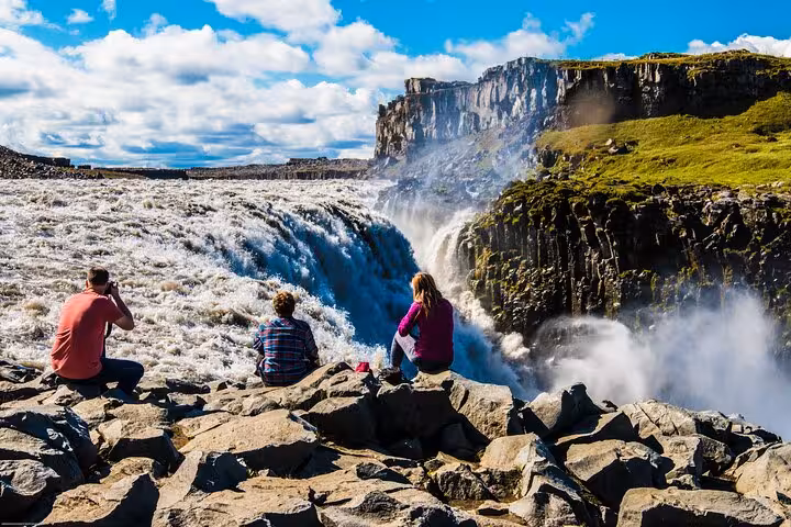 Tourists enjoy the breathtaking view of Dettifoss waterfall on the 4x4 Diamond Circle Day Tour from Akureyri.