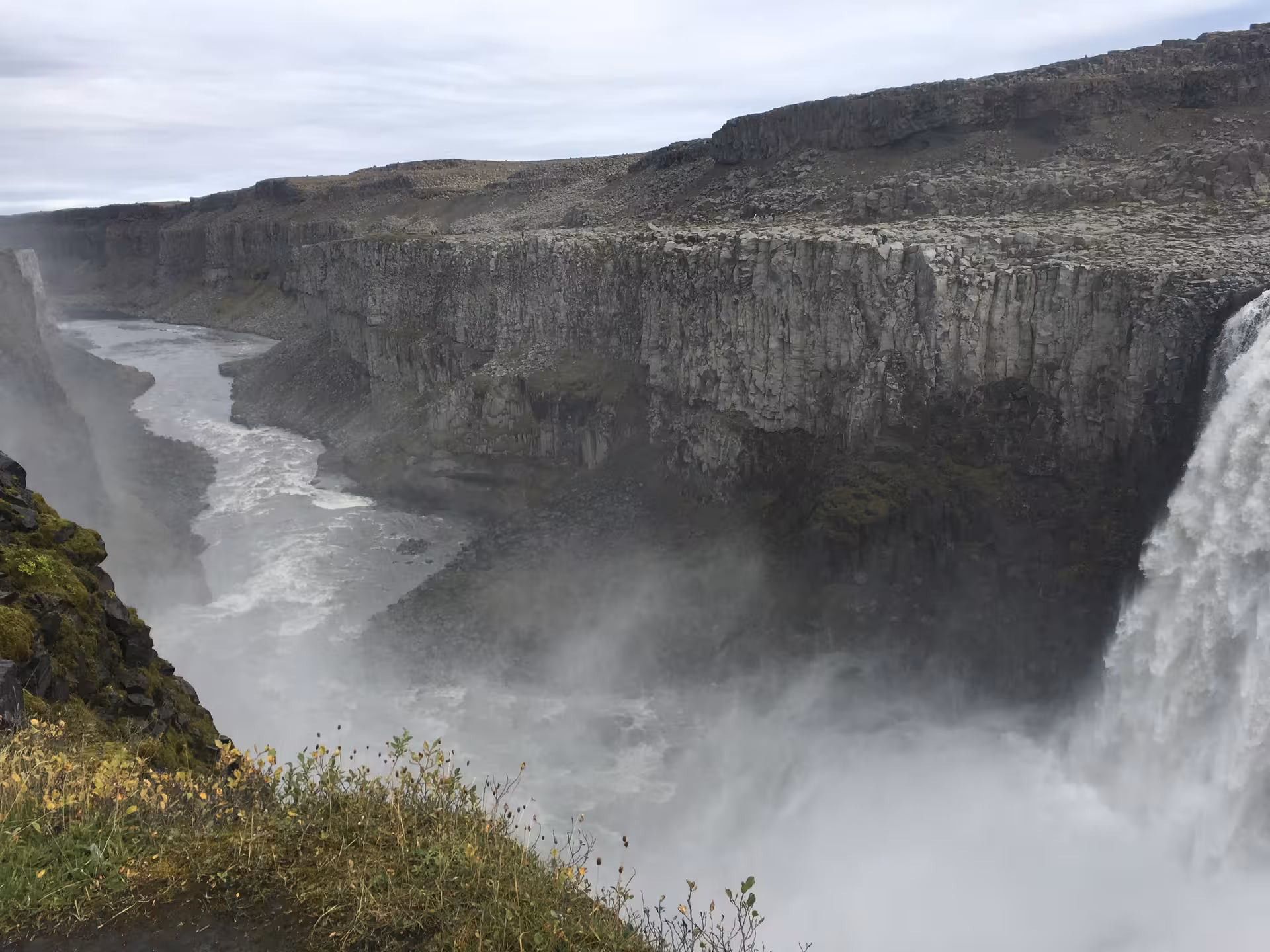 Majestic Dettifoss Waterfall cascading into a rugged canyon near Lake Myvatn under a cloudy sky.