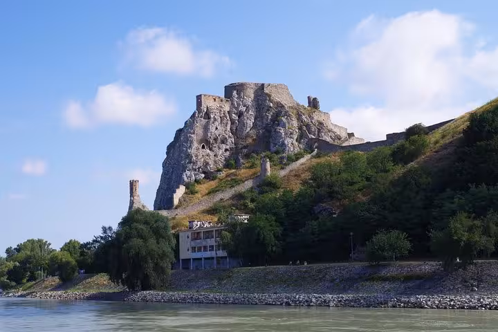 Riverside view of Devin Castle on rocky hill, highlight of Bratislava and Devin Castle private tour from Vienna