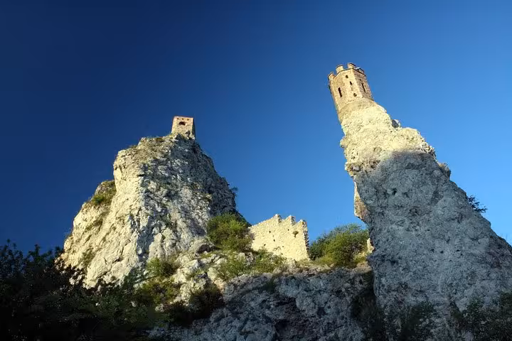 Looking up at Devin Castle cliff towers against blue sky, dramatic photo on Bratislava day trip from Vienna