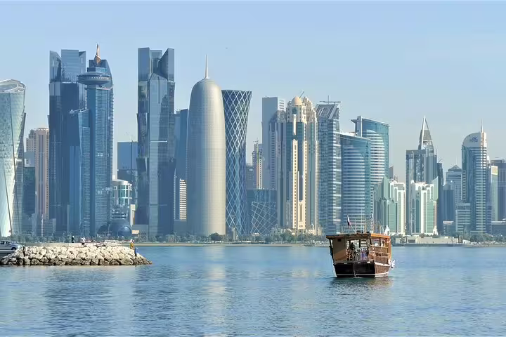 Traditional dhow boat sailing with Doha's stunning modern skyline in the background, perfect for transit city tours.