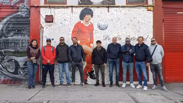 Tour group poses by Diego Maradona mural in Buenos Aires, guided football street art and history tour
